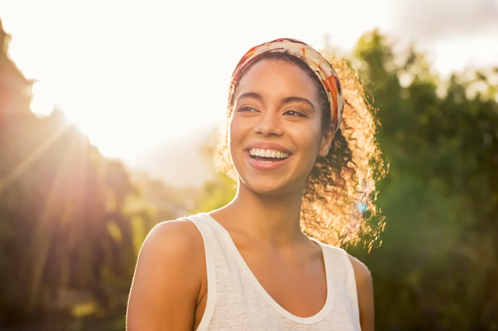 Portfolio 5 Woman smiling outdoors in sunlight, representing women’s hormone replacement therapy at Evolve HRT & Wellness in The Woodlands, TX